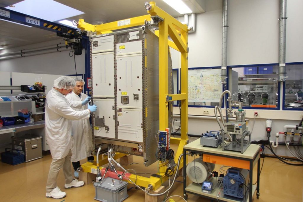 Two technicians point to large instrument box.