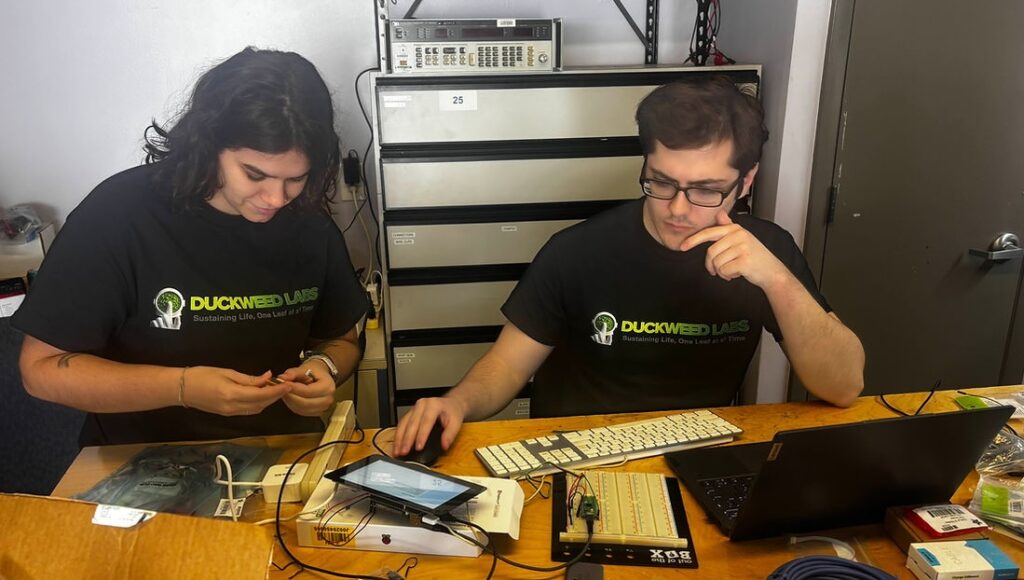 Two people working in electronics lab working on an electronic device